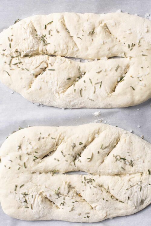Focaccia bread dough topped with herbs, ready to bake.