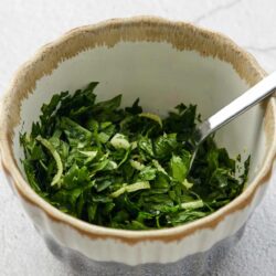 Chopped fresh herbs in a ceramic mixing bowl for baking or cooking.