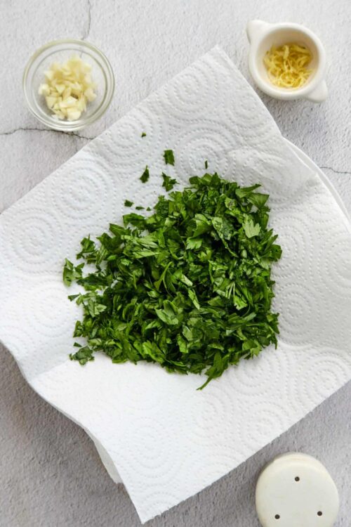 Chopped fresh parsley on paper towel for cooking or garnishing.
