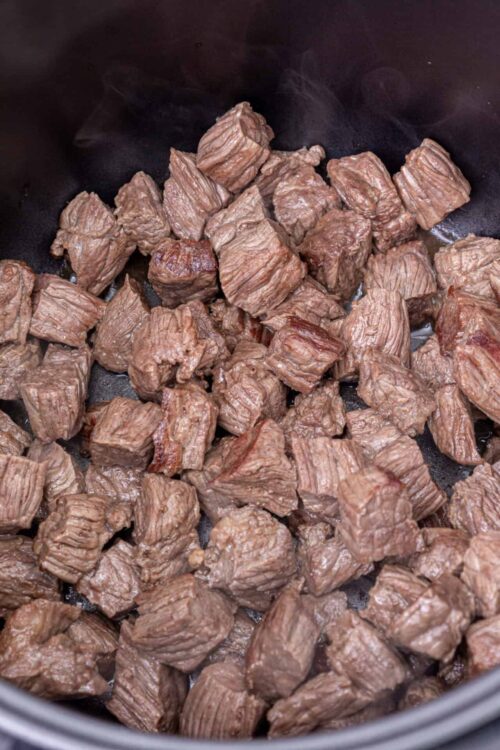 Cooked beef stew meat in a slow cooker or pot.