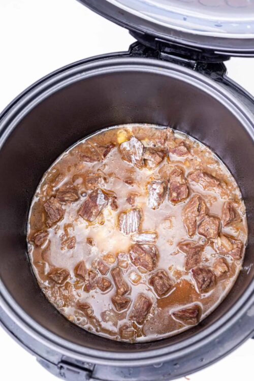 Savory beef stew cooking in a slow cooker.