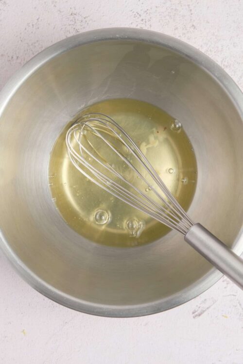 Smooth melted butter with a whisk in a metal mixing bowl, ready for baking recipes.