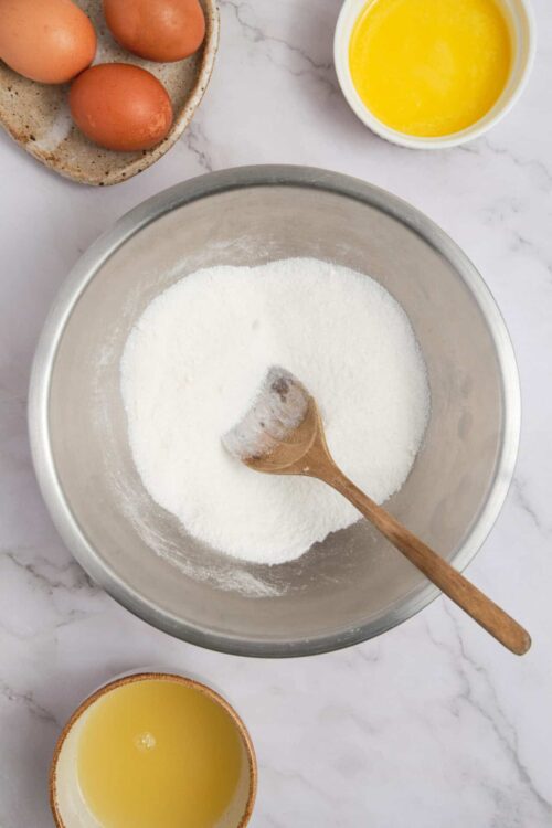 Fine baking ingredients including flour, eggs, melted butter, and a mixing bowl for delicious baked goods.