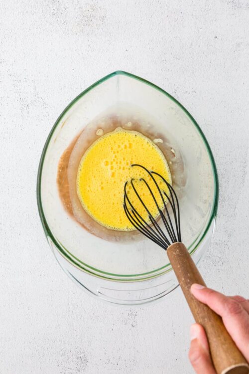 Whisking eggs in a glass bowl for baking or cooking recipes.