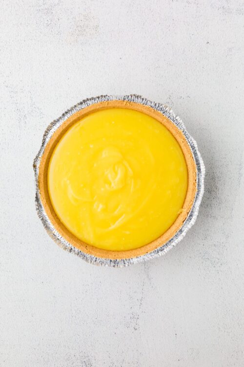 Lemon tart with a golden crust and vibrant yellow lemon filling in a foil tart pan.