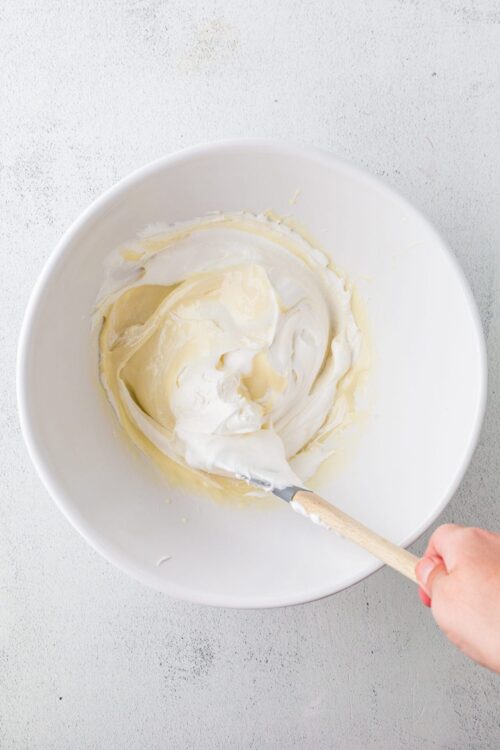 Cream cheese frosting in a white mixing bowl for baking recipes.