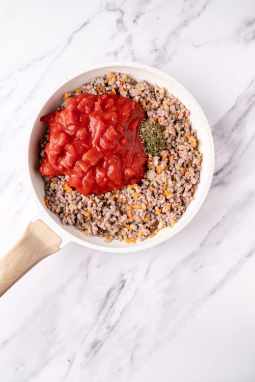 Ground beef with tomato sauce in a white skillet, ready for cooking or serving.