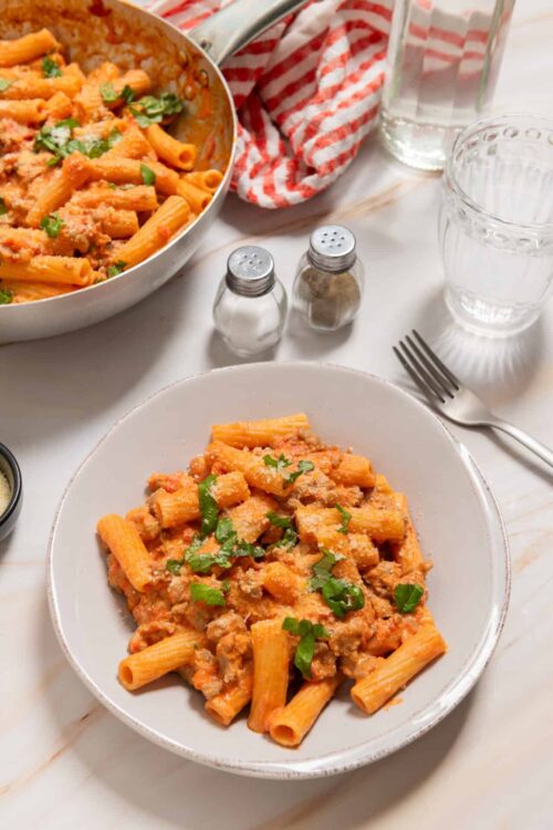 Creamy baked ziti pasta with tomato sauce and melted cheese, garnished with herbs.