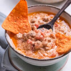 Creamy beef chili with tortilla chips in rustic bowl, perfect for comforting meals.