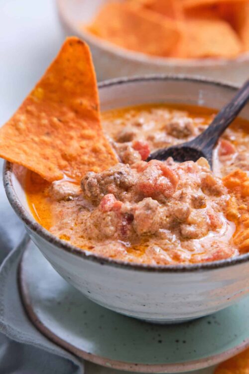 Creamy beef chili with melted cheese and tortilla chips in a rustic bowl.