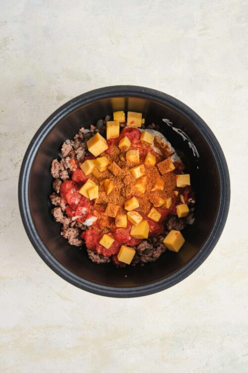 Ground beef, cheese, and seasonings in a slow cooker for easy taco filling.