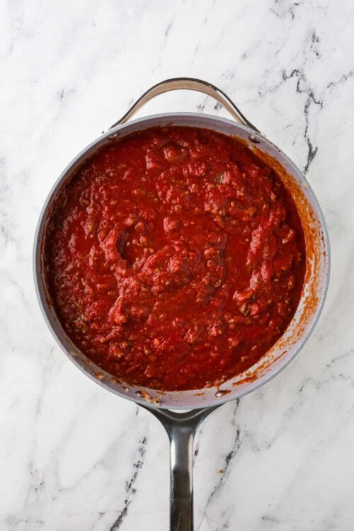 Rich homemade marinara sauce in a stainless steel saucepan.
