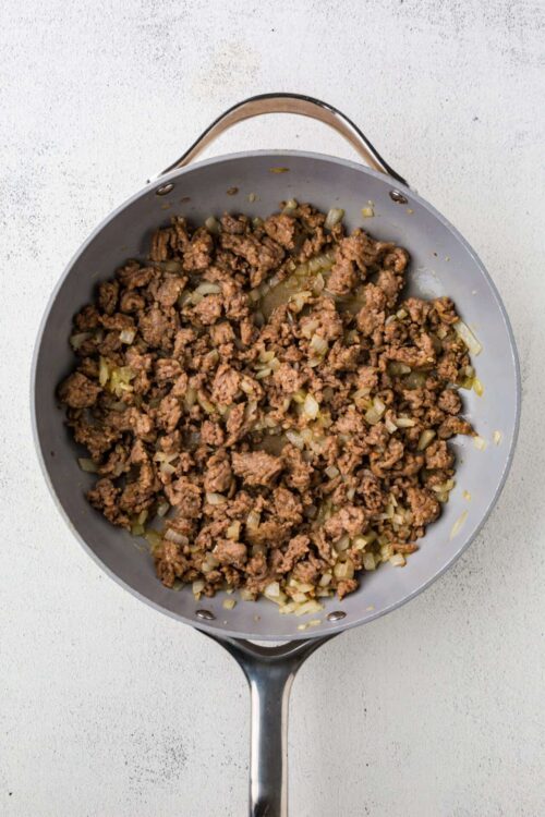 Ground beef and onions cooking in a skillet for comforting homemade meal.