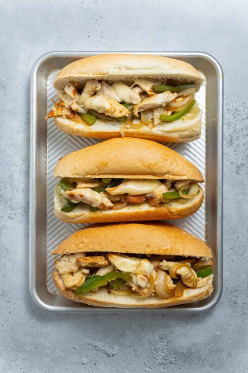 Fresh homemade chicken sandwiches with melted cheese and green peppers on hoagie rolls.