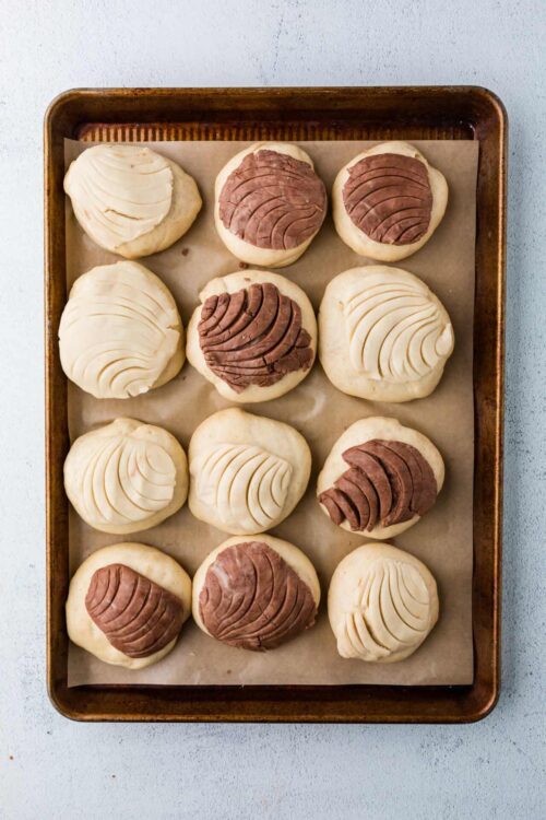 Buttery cookie dough balls topped with white and chocolate frosting, ready for baking.