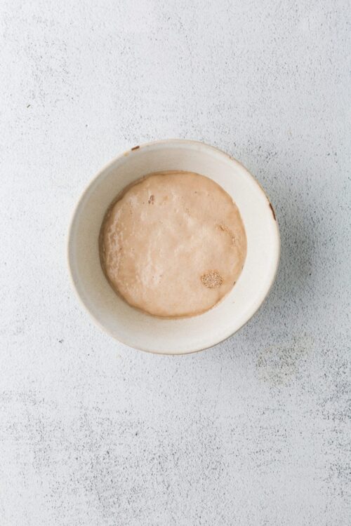 Creamy sourdough starter in a white bowl, ready for baking or bread making.