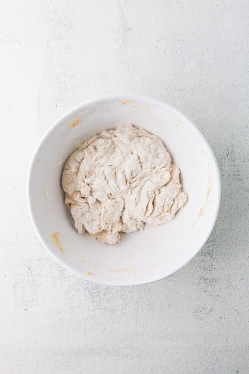 Flour dough mixture in a white mixing bowl for baking recipes.