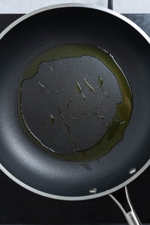 Golden olive oil in a black non-stick pan for baking or cooking.