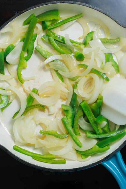 Sautéed green peppers and onions in a non-stick skillet for cooking or recipe preparation.