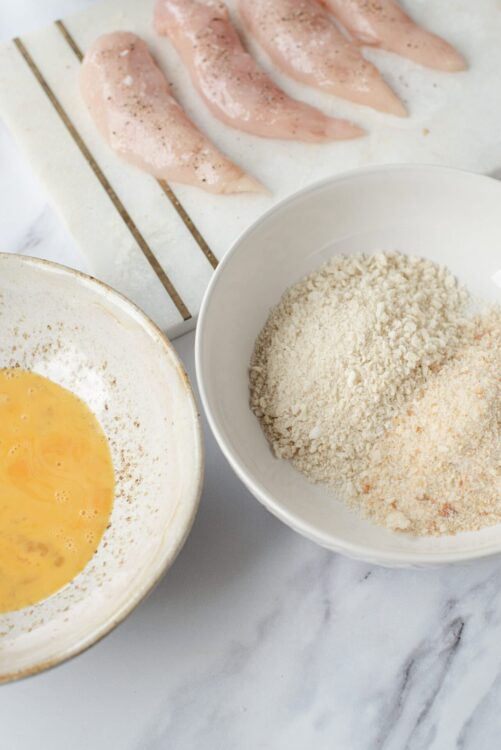 Baked Bree, breading ingredients, chicken cutlets, and seasoned breadcrumbs ready for coating. Perfect for homemade breaded chicken recipes.