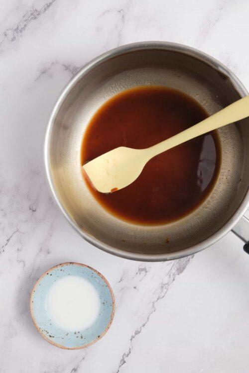 Sweet caramel sauce in a metal mixing bowl with a rubber spatula.
