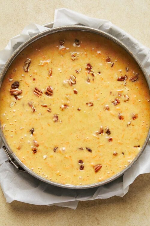 Creamy pecan pie filling in a baking dish with chopped pecans, ready to bake.