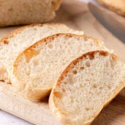 Soft, homemade bread slices on a wooden cutting board, fresh from the oven. Perfect for sandwiches or breakfast.