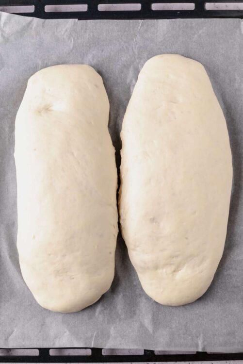 Soft, raw bread dough ready for baking on parchment paper.