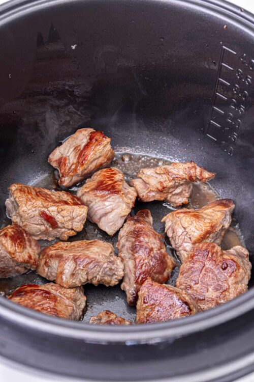 Tender beef chunks browned in a slow cooker, ready for flavorful stew or roast.