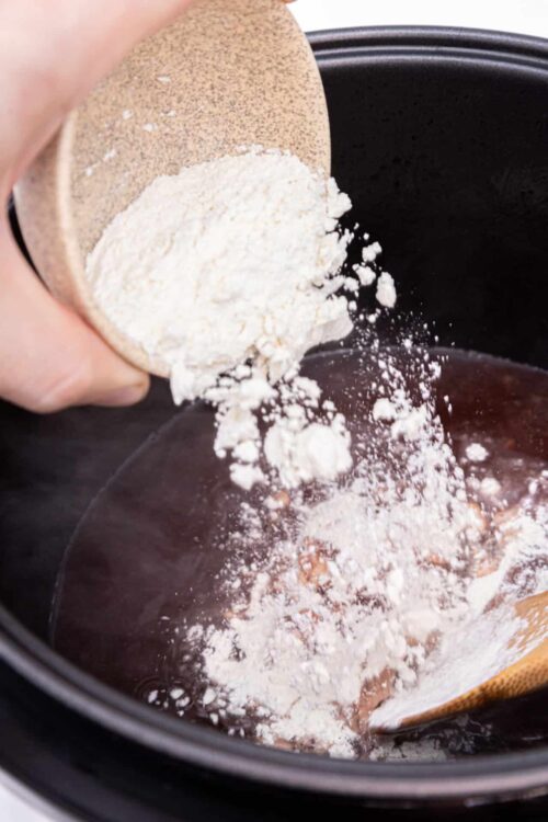 Flour being poured into a slow cooker for baking recipes or cooking preparation.