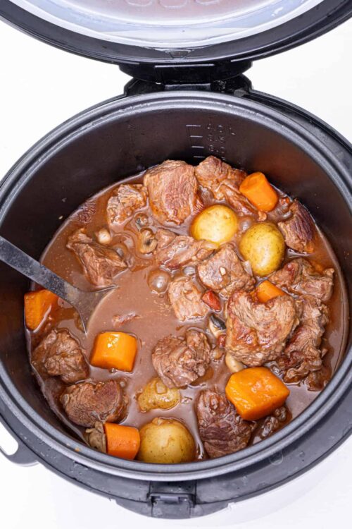 Slow cooker beef stew with tender beef chunks, carrots, and potatoes in rich gravy.