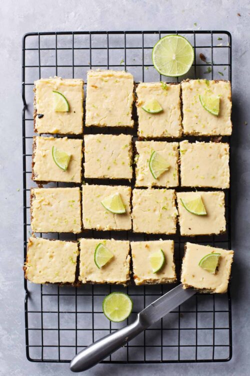 Lemon bars on a cooling rack garnished with lime wedges, perfect for citrus dessert recipes.