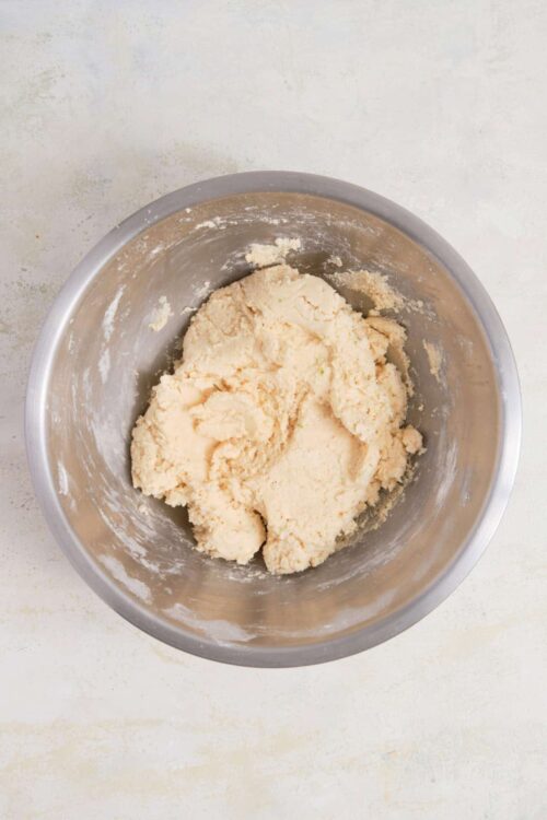 Buttery pie crust dough resting in a stainless steel mixing bowl for baking recipes.