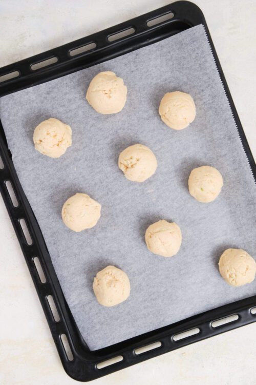 Soft cookie dough balls on a baking sheet ready to bake.
