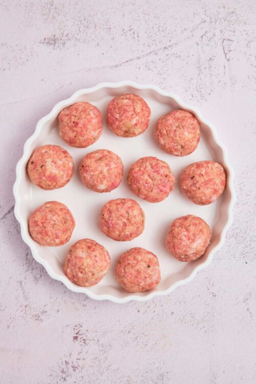 Minced chicken meatballs with herbs on a white ceramic plate.