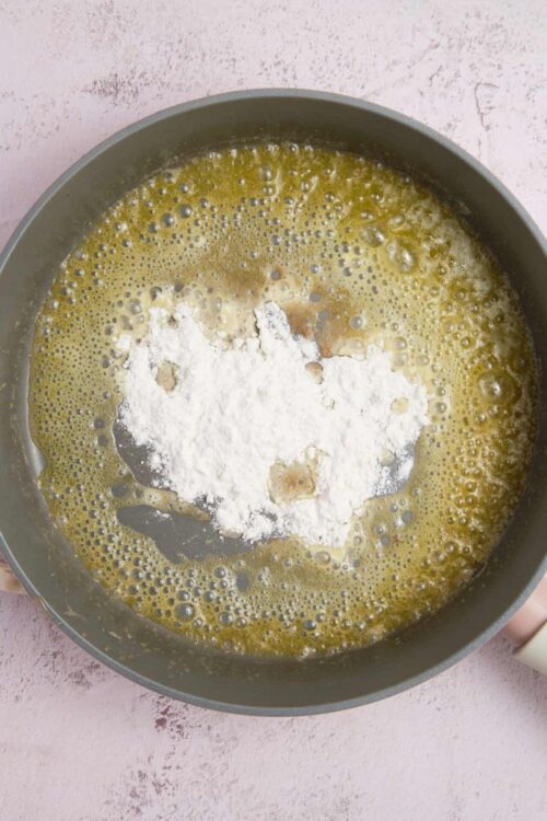 Flour added to a bubbling butter mixture for baking preparation.