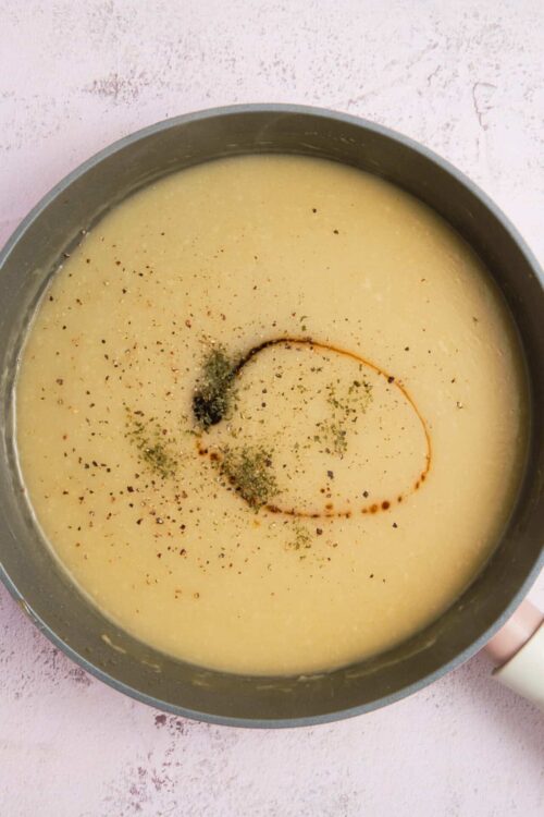Creamy soup with herbs and spices in a saucepan.