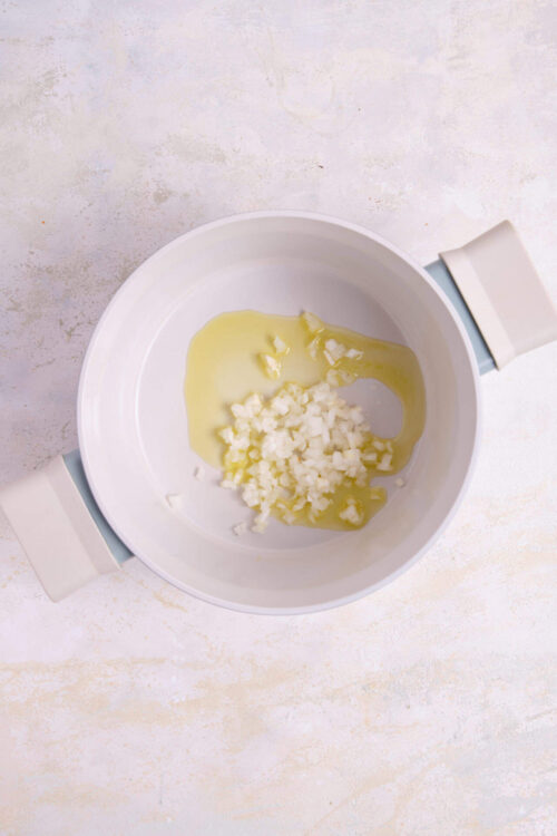 Chopped garlic and oil in a white skillet for cooking.