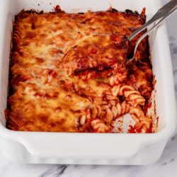 Cheesy baked pasta casserole in a white baking dish with golden melted cheese.