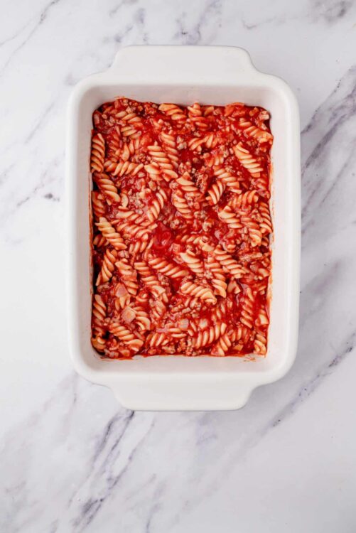 Roasted tomato and ground beef pasta bake in a white casserole dish.