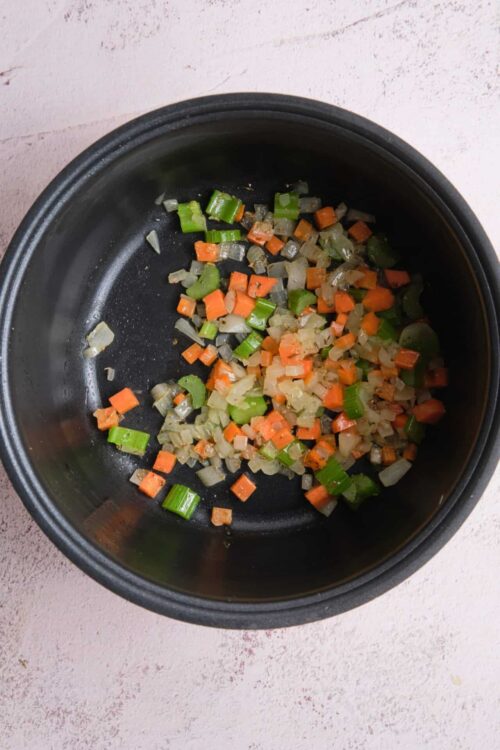 Diced vegetables in a slow cooker, onions, carrots, celery for soup base.
