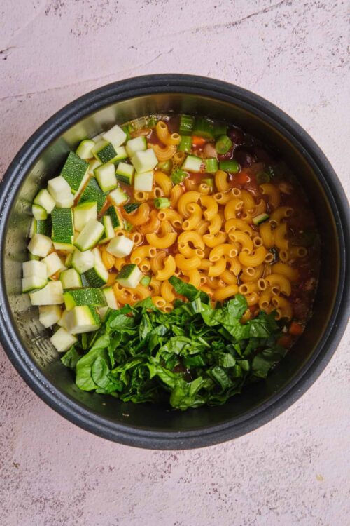 Cooked pasta with fresh chopped zucchini, scallions, and basil in a slow cooker.