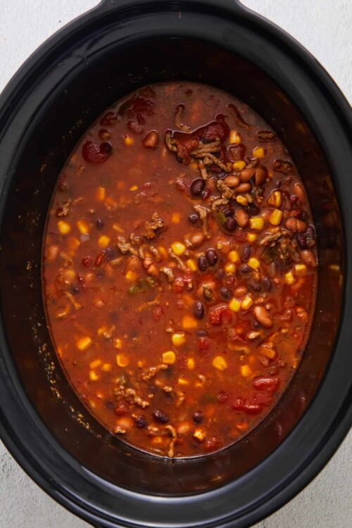 Chunky slow cooker beef chili with beans and corn in a black crockpot, easy beef chili recipe.