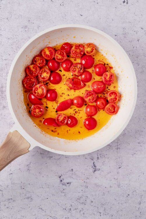 Juice cherry tomatoes in a white skillet with olive oil and herbs for a fresh, flavorful sauce.
