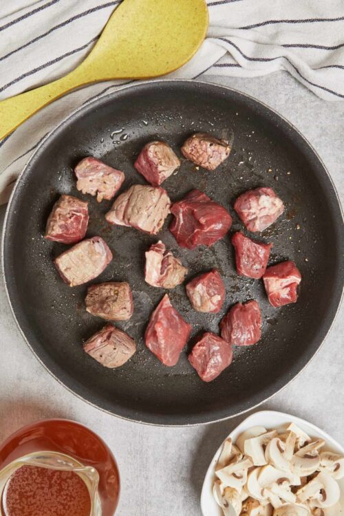 Searing cubed beef in a black skillet for a hearty beef stew.