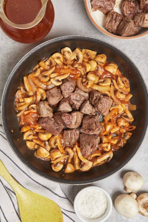 Juicy beef stew with mushrooms and onions in a skillet, ready to serve.