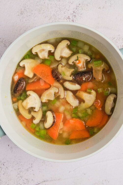 Cream of mushroom soup with chopped carrots and green onions in a white bowl for easy homemade soup.