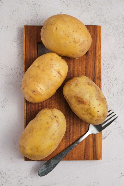 Yellow potatoes on a wooden board for baking or cooking.