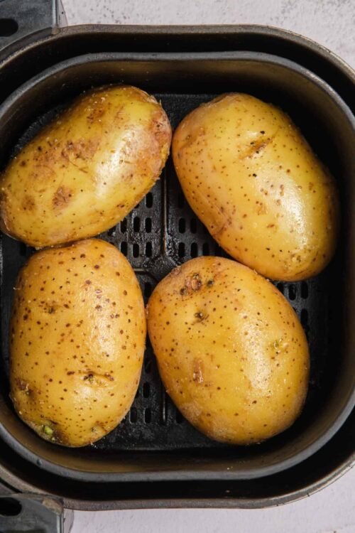 Baked potatoes in an air fryer with crispy skin and tender insides.