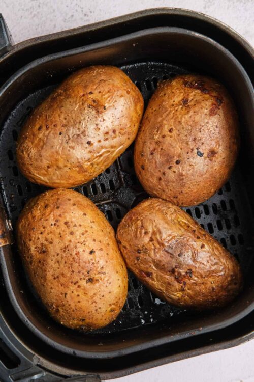 Golden brown roasted potatoes in air fryer basket.